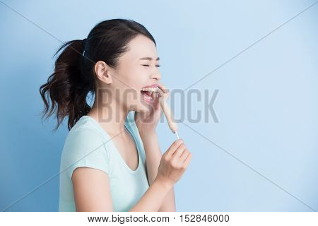 woman have sensitive teeth with ice isolatd on blue background asian