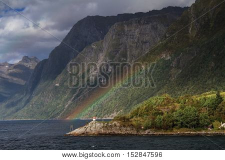 Rainbow and lighthouse at Hjorundfjord Fjordland Norway