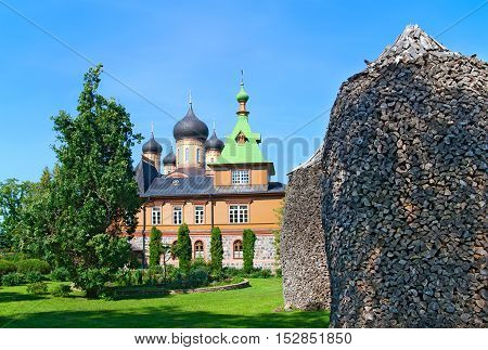 KUREMAE, IDA-VIRUMAA COUNTY, ESTONIA - AUGUST 21, 2016: Church of St Simeon and St Anna. Puhtitsa Dormition Convent. The Estonian Orthodox Church of Moscow Patriarchate. Foreground are woodpiles