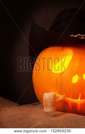 Pumpkin on Halloween in a cowboy hat with a pipe on an black background