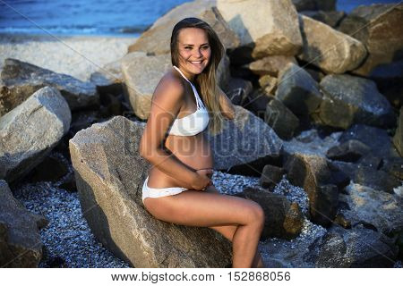 Pregnant smiling woman on the sandy beach