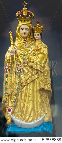 Vadipatti India - October 22 2013: Closeup of golden Virgin Mary statue at Vadipatti Arockia Annai Shrine. She holds baby jesus. Both wear a crown. Slim crescent moon present. Plenty of jewels.