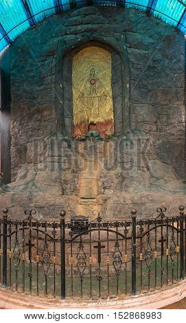 Vadipatti India - October 22 2013: Golden Virgin Mary fresco in a grotto at Vadipatti Arockia Annai Shrine. She holds rosary and stands on the head of black snake. Image of god and angels. She is worshiped as protector of good health.