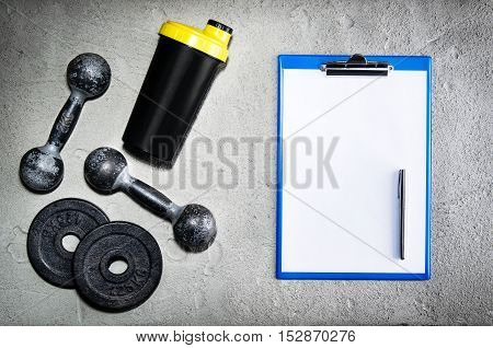Fitness or bodybuilding concept background. Product photograph of old iron dumbbells on grey, conrete floor in the gym with blank page. Photograph taken from above, top view with lots of copy space