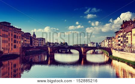 View from the river to the famous italian medieval bridge - Ponte Vecchio in Florence with blue sky and clouds, travel outdoor Italy sightseeing background