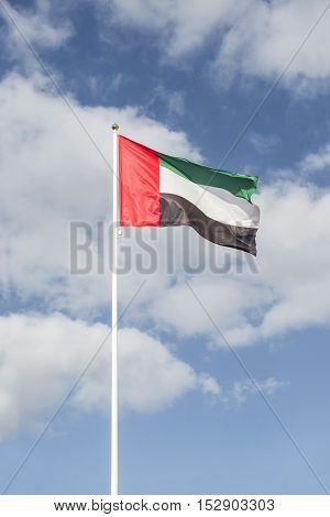 National flag of United Arab Emirates. Hoisted against bright blue sky.