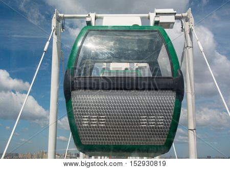 Close up shot of ferric wheel gren gandola with city in background