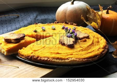 American pie with pumpkin and mascarpone on the table with fresh pumpkin and maple leaves