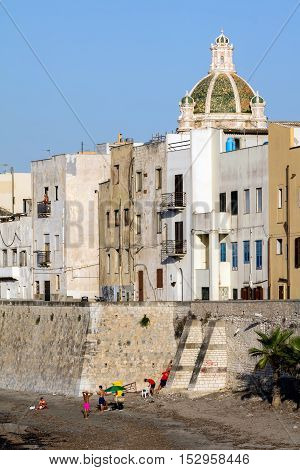 TRAPANI ITALY - AUGUST 10 2016: Waterfront of Trapani Sicily with the dome of the 15th century's Saint Lorenzo's Cathedral.