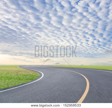 road curve with green grass and blue sky white cloud background