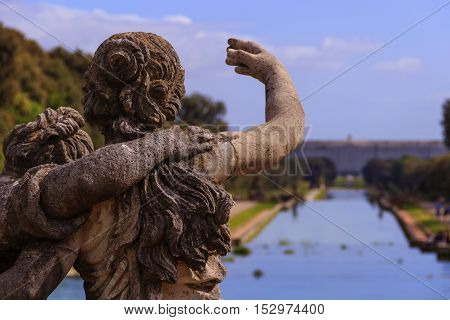 Caserta, Italy, May 1, 2016: Caserta Palace Royal Garden. In the foreground, marble sculptures. Iinspired by the park of Versailles, it is 3 kilometer long.Caserta Palace Royal Garden.