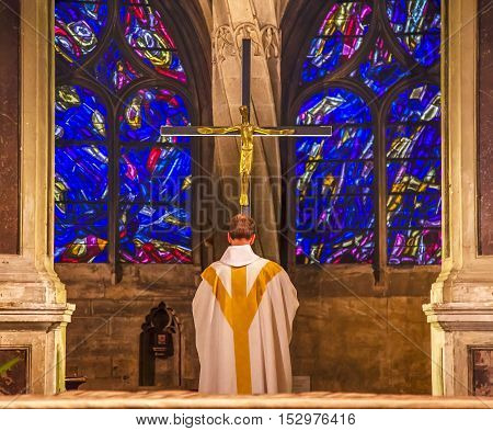 PARIS, FRANCE - MAY 31, 2015 Priest Praying Crucifix Cross Altar Column Shape of Palm Tree Stained Glass Saint Severin Church Paris France. Saint Severin one of oldest churches Paris located in the Latin Quarter. Built in the 1500s