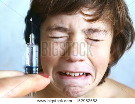 doctor holding a syringe with injection vaccination. Boy is afraid. Teen boy in fear of injection.