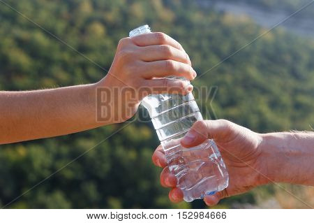 Man sends woman bottle of water on camping trip in forest on hot summer sunny day