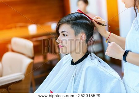 Beauty, hairstyle, treatment, hair care concept, young woman and hairdresser cutting hair at hairdressing salon. Hairdresser cuts happy girl's hair. Hairstylist serving client at barber shop