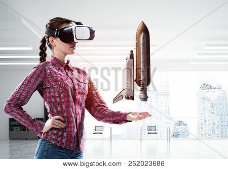 Young Caucasian Woman In Modern Office Interior Trying Virtual Reality Helmet And Viewing Space Shut