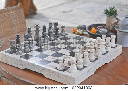 A Set Of Stone Handmade Chess On A Wooden Table In The Living Room Before The Game Starts
