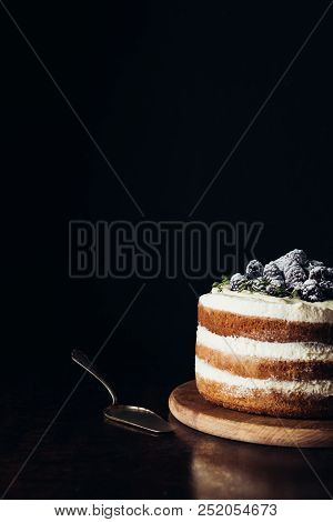 Close-up Shot Of Delicious Blackberry Cake On Wooden Cutting Board And On Black With Cake Server