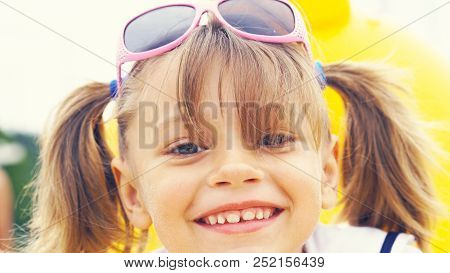 Portrait Of A Cute Smling Girl Wearing Sunglasses On The Forehead, , Sitting On Summer Beach.