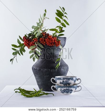 Two Kups Of English Porcelain Fore Soup, Bunch Of Green Peper And A Rough Ceramic Jug With Ash Berri