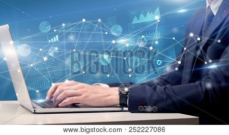 Businessman typing on laptop with linked reports charts grapghs around