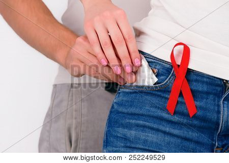 Safe sex healthcare concept. Doctor wearing white coat with pinned a red ribbon as symbol of hiv aid