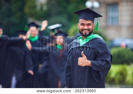 Portrait Of Successful Indian Student In Graduation Gown Thumb Up