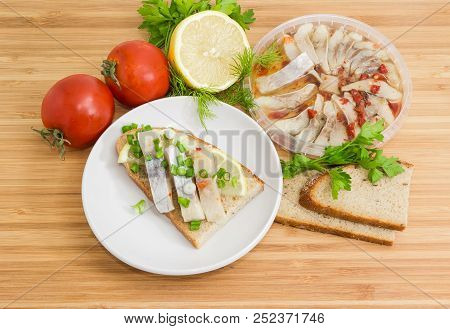 Open Sandwich Made Of Brown Bread, Slices Of Fillet Of Pickled Atlantic Herring, Fresh Lemon And Cho