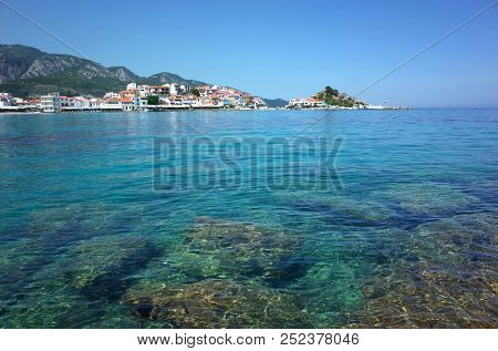 Kokkari, Samos island, Greece - 15 May, 2018: Waterfront view of Kokkari fishing village with stones bottom seen under crystal clean water