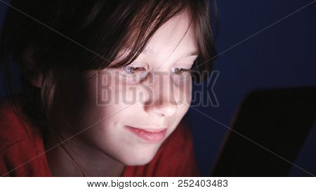 Caucasian Girl Lying In Bed Playing Tablet In Social Internet In Dark Blue Light Under Blacket. Chil