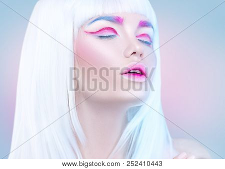 Breauty high fashion model girl portrait with white short hair, trendy pink eyeline, gradient lips. Futuristic art make-up in white, blue and pink. Beautiful makeup, colorful eyebrows. Make up artist