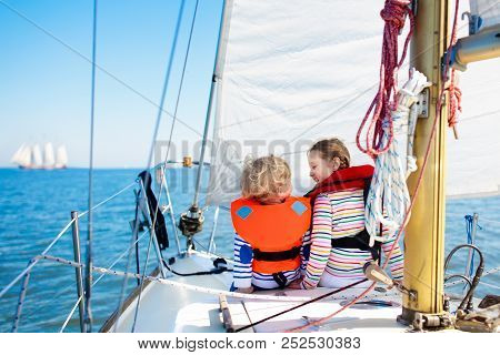 Kids Sail On Yacht In Sea. Child Sailing On Boat. Little Boy And Girl In Safe Life Jackets Travel On