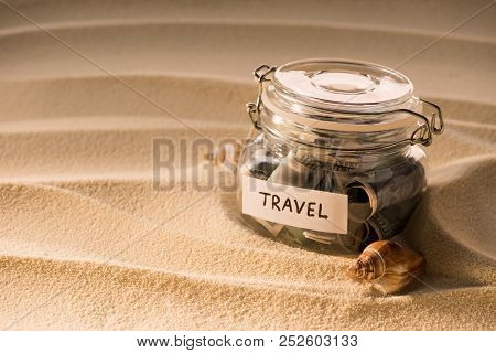 Close Up View Of Glass Jar With Dollars On Sandy Beach With Seashells, Traveling Concept