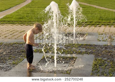 Cute Toddler Playing In Fountain. Concept Of Happiness And Carefree Childhood