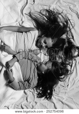 Girls On White And Pink Bed Sheets Background. Schoolgirls In Pink Pajamas Wallow On Colorful Pillow