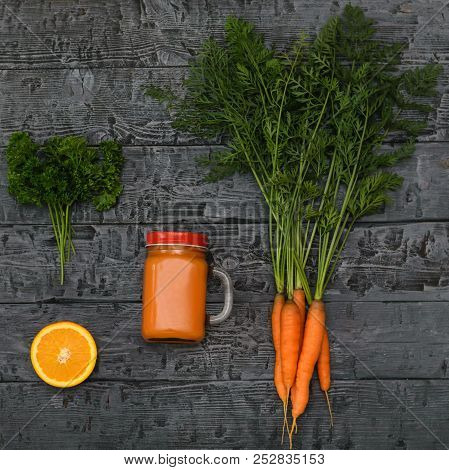 Freshly Made Carrot Smoothie, Bunch Of Carrots And Orange On A Rustic Table. The View From The Top. 