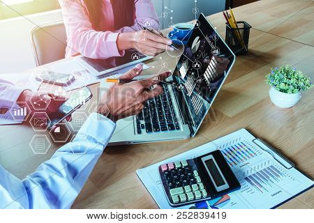Two Colleagues Discussing Data With Smart Phone And New Modern Computer Laptop On Desk Table. Busine