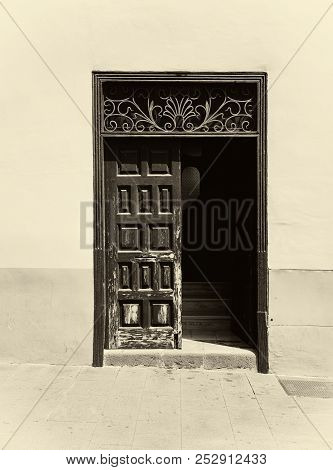 A Sepia Image Of An Old Wooden Door With Panels In A Traditional Spanish House Half Open Revealing S