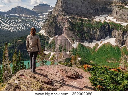 Woman In Gray Coat Stands Above Grinnell Lake On Sunny Day