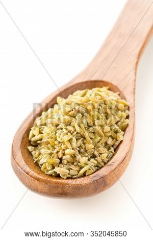 Heap Of Uncooked, Raw Freekeh Or Firik, Roasted Wheat Grain, In Wooden Spoon Over White Background W