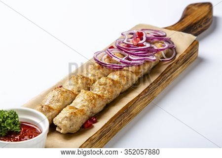 Lula-kebab Of Chicken With Onions And Hot Red Sauce. Lula Is Served On A Wooden Tray. White Backgrou