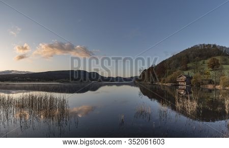 Stunning Sunrise Autumn Fall Landscape Image Of Ullswater In Lake District With Golden Sunlight