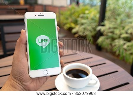 Chiang Mai, Thailand - Feb.17,2020: Man Holding Apple Iphone 8 Plus With Line Apps On Screen On Wood