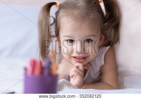 Beautiful Girl Draws With Pencils In Bed. Little Girl Two Years Paints Coloring Book Lying On The Be