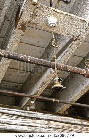 A Very Old Electrical Lighting Receptacle Hangs From The Joices Of A Warehouse