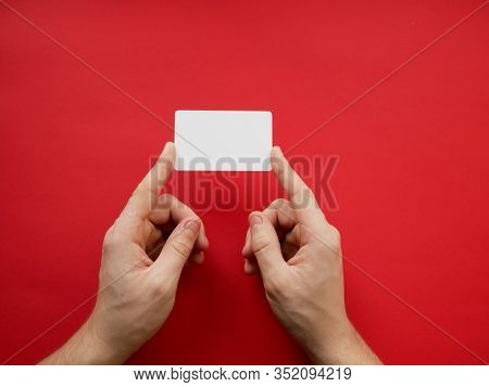 Female Hands Holding Blank White Business Card On Red Background. Top View