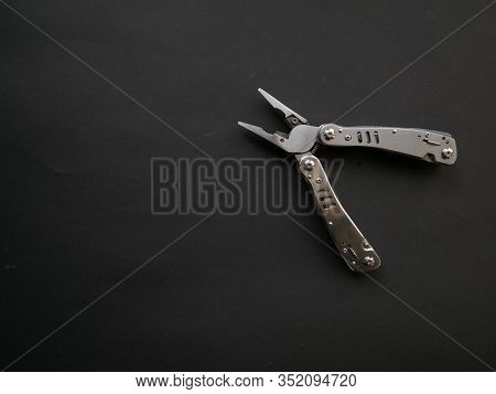 Multi Tool With Steel Handles On A Black Paper Background. Top View