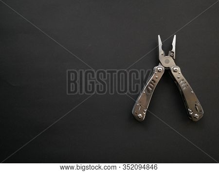Multi Tool With Steel Handles On A Black Paper Background. Top View