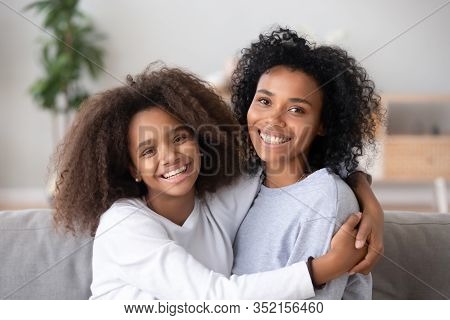 Happy African Mother And Teen Daughter Embracing Looking At Camera