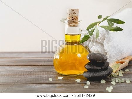 Soft Towel Placed On Lumber Table Near Fresh Olive Oil And Salt In Spa Salon